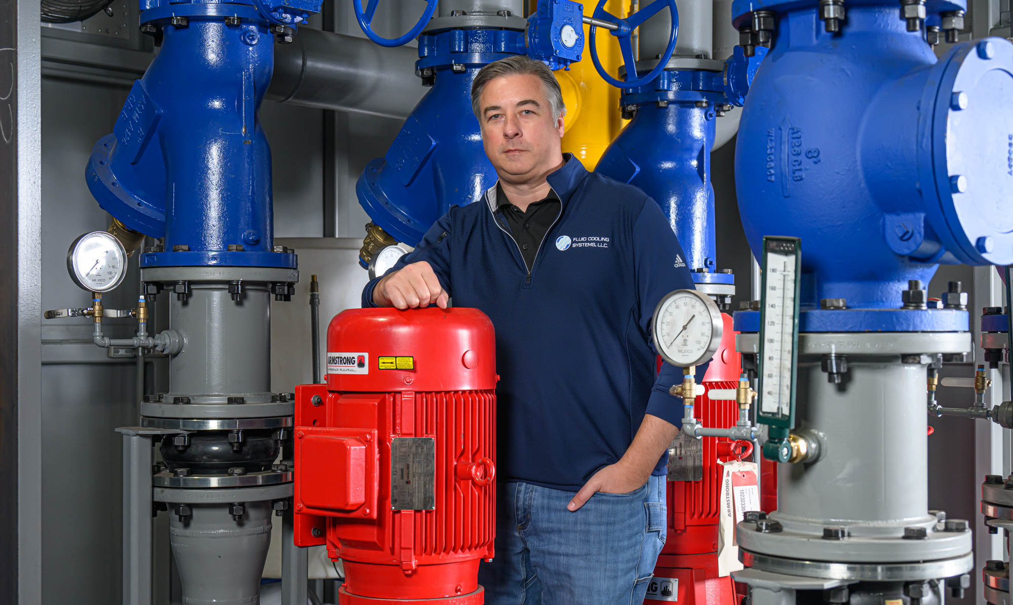 Man standing in among large Industrial fluid cooling pumps.
